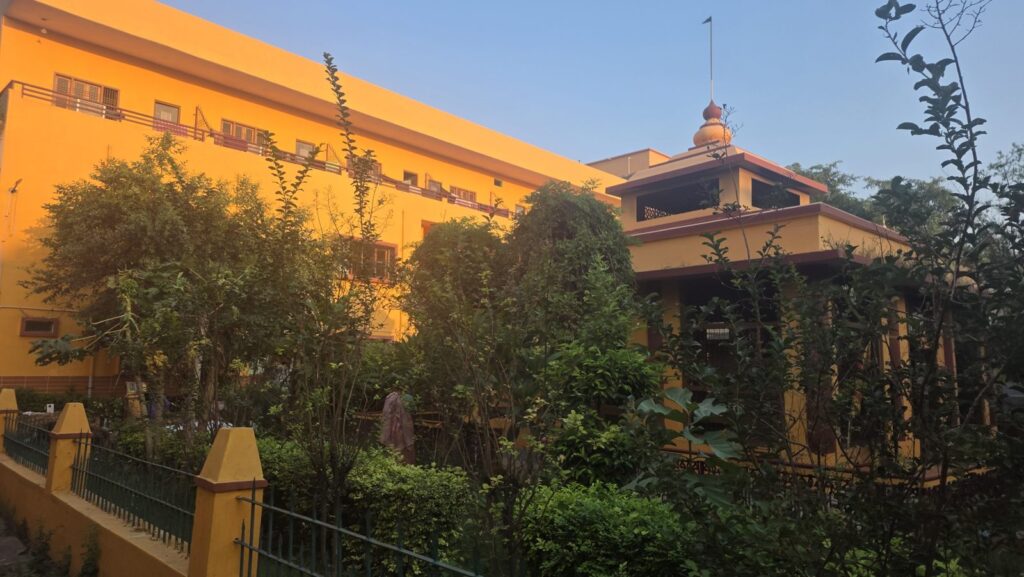Yellow buildings and garden inside the Mumukshu Bhawan campus near Assi, Varanasi
