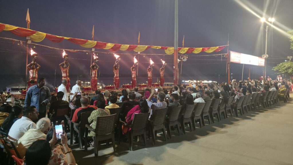 Rows of devotees seated facing the aarti platform at Assi Ghat before dawn