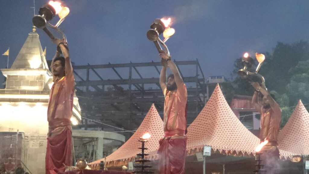 Priests raise brass aarti lamps during the morning Ganga aarti at Assi Ghat, Varanasi, before sunrise